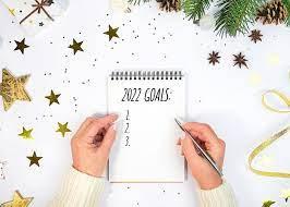 Person holding a pen over a piece of paper. "2022 Goals" written on top with numbers one through four