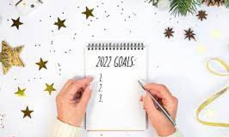 Person holding a pen over a piece of paper. "2022 Goals" written on top with numbers one through four